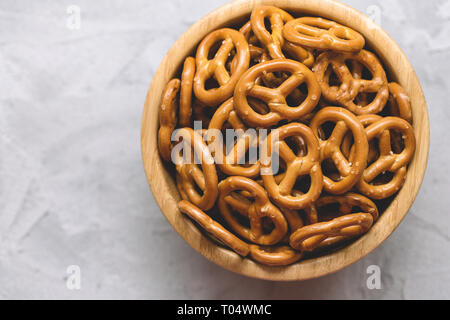 Traditional salty mini pretzels in wooden bowl on a gray backround. Copy space. Stock Photo