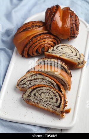 Sliced and whole poppy seed rolls on a cutting board Stock Photo