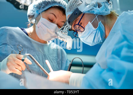 Portrait of professional surgeons during surgery on a blue background. Concept surgery, medicine. Surgeons are working on a complex operation Stock Photo