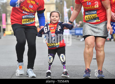 Five-year-old Harmonie-Rose Allen, who lost her limbs to meningitis, crossing the finishing line in the Bath Half Marathon with the help of her teacher Antony Wainer and her auntie Hannah Hall. Stock Photo