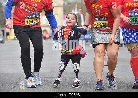 Five-year-old Harmonie-Rose Allen, who lost her limbs to meningitis, crossing the finishing line in the Bath Half Marathon with the help of her teacher Antony Wainer and her auntie Hannah Hall. Stock Photo