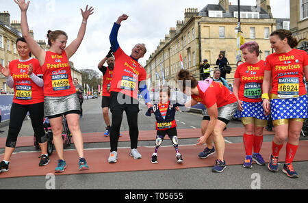 Five-year-old Harmonie-Rose Allen, who lost her limbs to meningitis, crossing the finishing line in the Bath Half Marathon with the help of her teacher Antony Wainer and her auntie Hannah Hall. Stock Photo