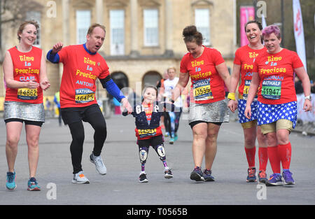 Five-year-old Harmonie-Rose Allen, who lost her limbs to meningitis, crossing the finishing line in the Bath Half Marathon with the help of her teacher Antony Wainer and her auntie Hannah Hall. Stock Photo