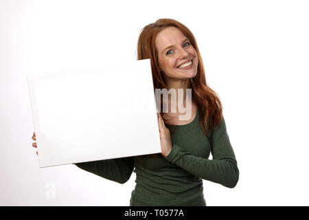Red haired woman with green sweater smiled and holds a sign Stock Photo