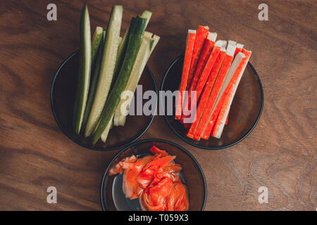 Ingredients for the preparation of sushi in plates on the table, which include pickled ginger, rice, cucumbers, melted cheese, top view 2019 Stock Photo