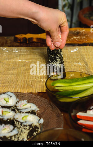 Women's hands close-up in a restaurant sprinkle sesame oil during the preparation of sushi 2019 Stock Photo