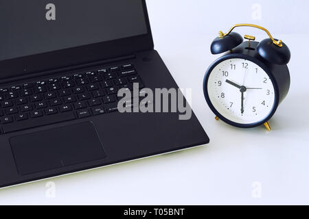 a work desk with a computer and office accessories and an alarm clock measuring the time running away. The concept of urgent deadlines at work Stock Photo