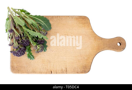 Early purple sprouting broccoli spring vegetable, with wooden food cutting board. Isolated on white. Overhead view. Stock Photo