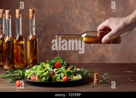 Vegetable salad with olive oil pouring from a small bottle. Copy space. Stock Photo