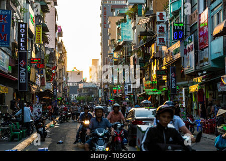 Ho Chi Minh City, Saigon, Vietnam. Sun is setting in the background in the busy streets in Pham Ngu Lao, Backpacker District. Stock Photo