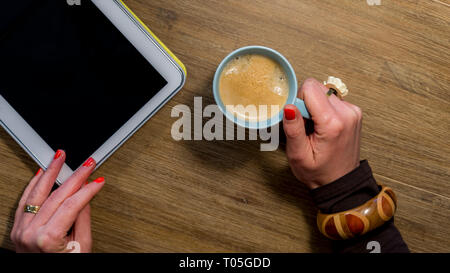 womans hands with nail polish holding coffee and tablet Stock Photo
