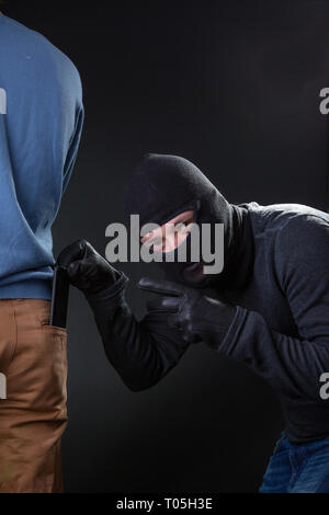 Burglar in bachelor steals wallet from pocket in man. Stock Photo