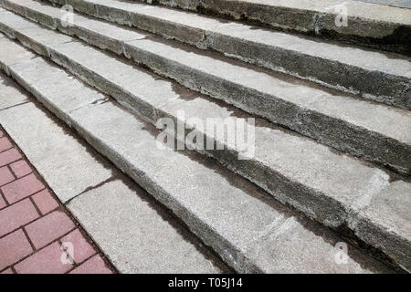 View from above of gray concrete stairs leading to colorful pavement outdoors on sunny day. Stock Photo