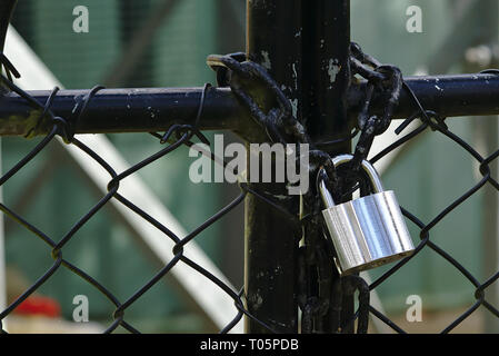 Close up look of new shiny silver padlock on old black chain Stock Photo