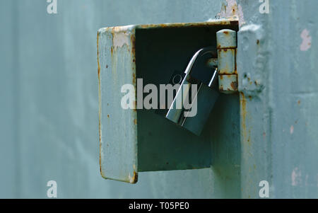 Close up view of silver padlock securing corrosive light blue door hinge Stock Photo