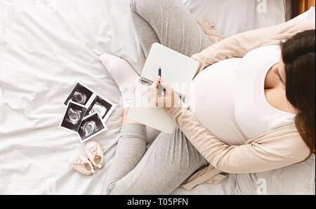 Pregnant woman making packing list for maternity hospital Stock Photo