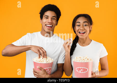 Happy teenage couple eating popcorn, watching movie Stock Photo
