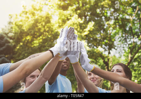 Group of volunteers making high five in park Stock Photo