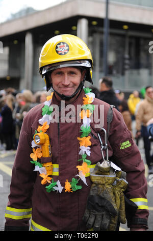 London, UK. 17th Mar, 2019. A London Fire Brigade firefighter wearing a green, white and orange garland on the the annual St Patrick’s day parade in Central London, England, United Kingdom.  Festivities are held each year to commemorate the saint of Ireland, St Patrick, but for many people now the Christian message has been replaced by a good excuse for a street party, washed down with several pints of Guinness. Credit: Michael Preston/Alamy Live News Stock Photo