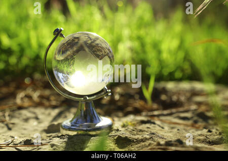 small crystal globe in front of sunset. travel and global issues concept Stock Photo