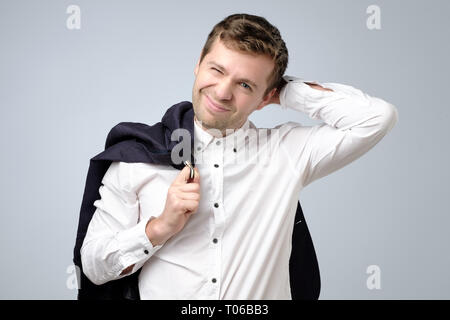Doubtful handsome man in suit standing touching his head and looking at caemra, thinking. Stock Photo
