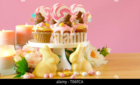 Easter theme candy land drip cupcakes decorated with chocolate bunnies in party table setting with copy space. Stock Photo