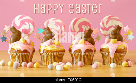 Easter theme candy land drip cupcakes decorated with chocolate bunnies in party table setting, with Happy Easter greeting text. Stock Photo