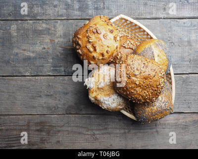 Assortment of tasty organic buns in a basket on a rustic kitchen table Stock Photo