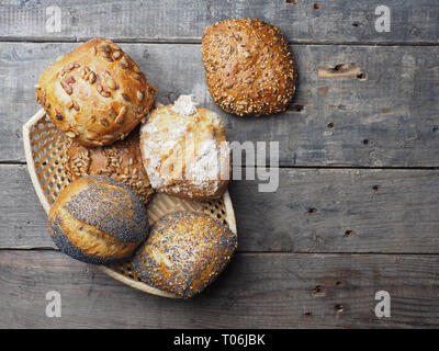 Assortment of tasty organic buns in a basket on a rustic kitchen table Stock Photo