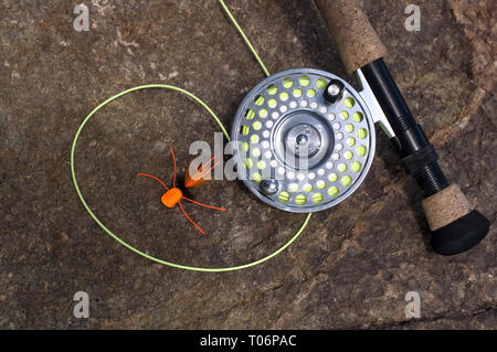Fly fishing Rod and Reel with Orange Spider Lure on Wet Rocks