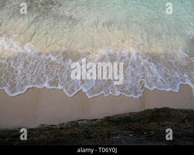 Beautiful patterns made by the waves gently lapping against the soft white sand of a tropical beach Stock Photo