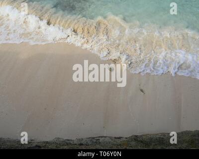 Foaming waves gently pulling back to the ocean in a continuous pattern in a tropical island Stock Photo
