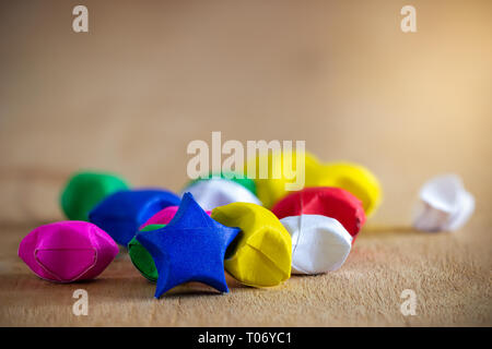 Multicolor paper star laid on wooden table with morning sunlight. Stock Photo