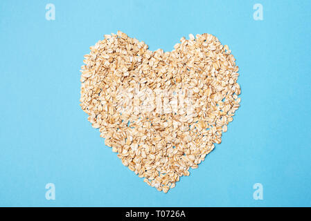 Oats in shape of heart on blue background. Healthcare, healthy eating, lifestyle concept. Vegan, keto or vegetarian diet food Stock Photo