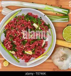 Raw minced beef and vegetables chilled chillis and garlic with wooden chopping board Stock Photo