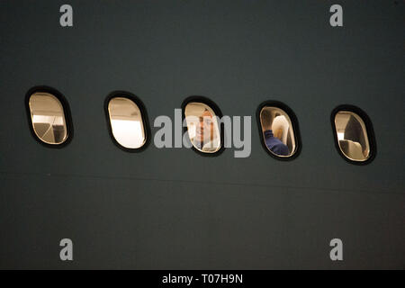 Glasgow, UK. 18th Mar, 2019. Liam Palmer (centre window) onboard with the Scotland Football Team seen boarding their luxury jetliner private aircraft in the early hours seen at Glasgow Airport moments before departing for Kazakhstan to play a game on Wednesday. The flight was due to take off at 11pm, however due to an unforeseen problem where the pilot had to come out of the flight deck and onto the tarmac and speak with ground crew, the flight eventually took off in the early hours of today. Credit: Colin Fisher/Alamy Live News Stock Photo