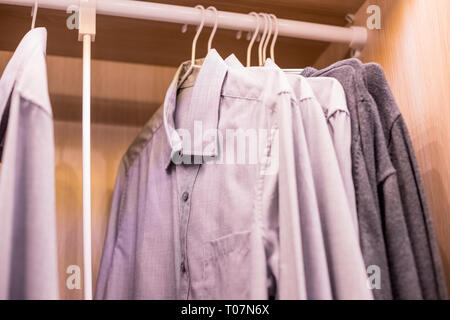 Many shirts hanging on a rack.Row of men's suits hanging in closet. concept of buy and sell, business man.Man's closet. Hangers with shirts closeup Stock Photo