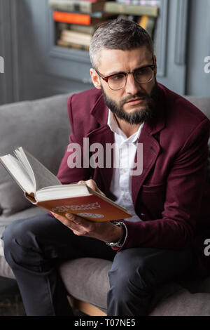 Man wearing white shirt and jacket reading book having break from work Stock Photo