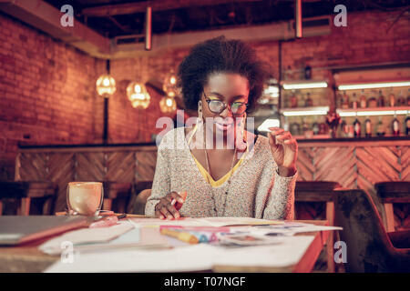 Serious African-American female thoroughly looking at papers in cafeteria Stock Photo