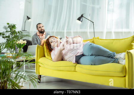 Relaxed overweight girl lying on yellow sofa Stock Photo