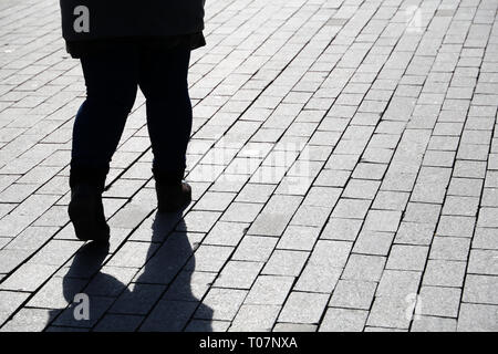 Silhouette of fat woman walking down the street, black shadow on pavement. Thick legs in jeans, concept of overweight, diet, loneliness, dramatic life Stock Photo