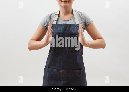 Woman chef cook in a denim apron holds your empty hands open on a white background. Mock up copy space concept . Stock Photo