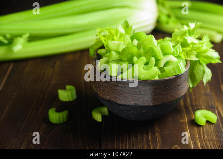 Cutted celery sticks in ceramic bowl on wooden background Stock Photo