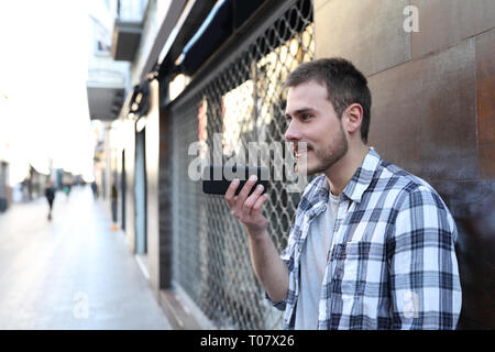 Guy using voice recognition on smart phone outside in the street of an old town Stock Photo