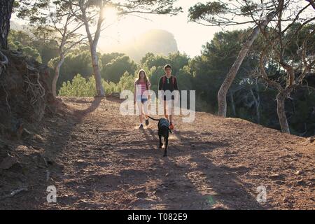 Happy teenagers and dog out walking in forest Stock Photo