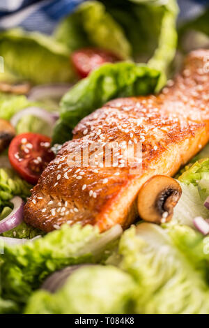 Roasted salmon fillet with fresh vegetable salad tomatoes mushrooms and sesame. Stock Photo