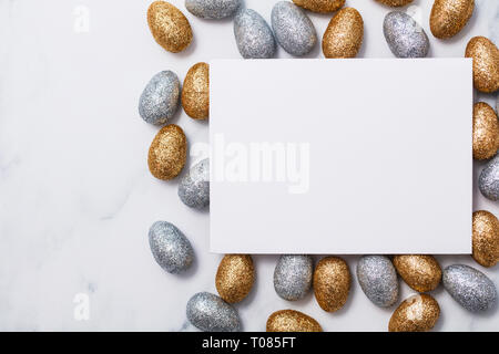 Easter background with a blank white card and glitter easter eggs Stock Photo
