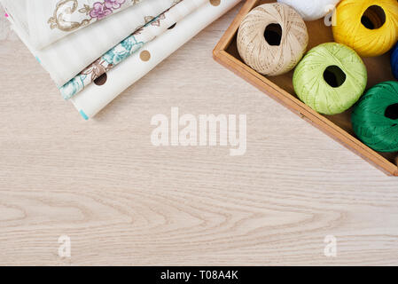 Composition with sewing, knitting threads and fabrics on gray wooden background, top view Stock Photo