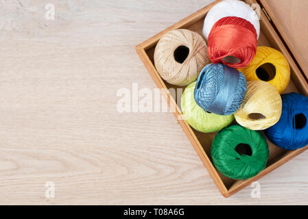 Set of colorful threads for knitting, crocheting in wooden box on the table Stock Photo