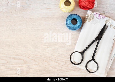 Composition with sewing, knitting threads, fabrics and antique scissors on gray wooden background, top view Stock Photo